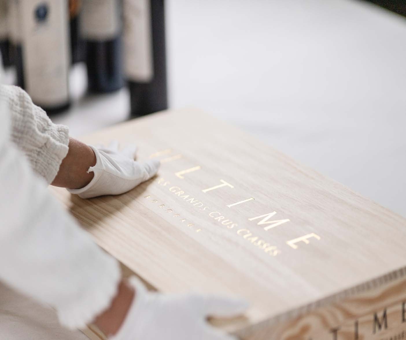 A white-gloved hand on a wooden collector case